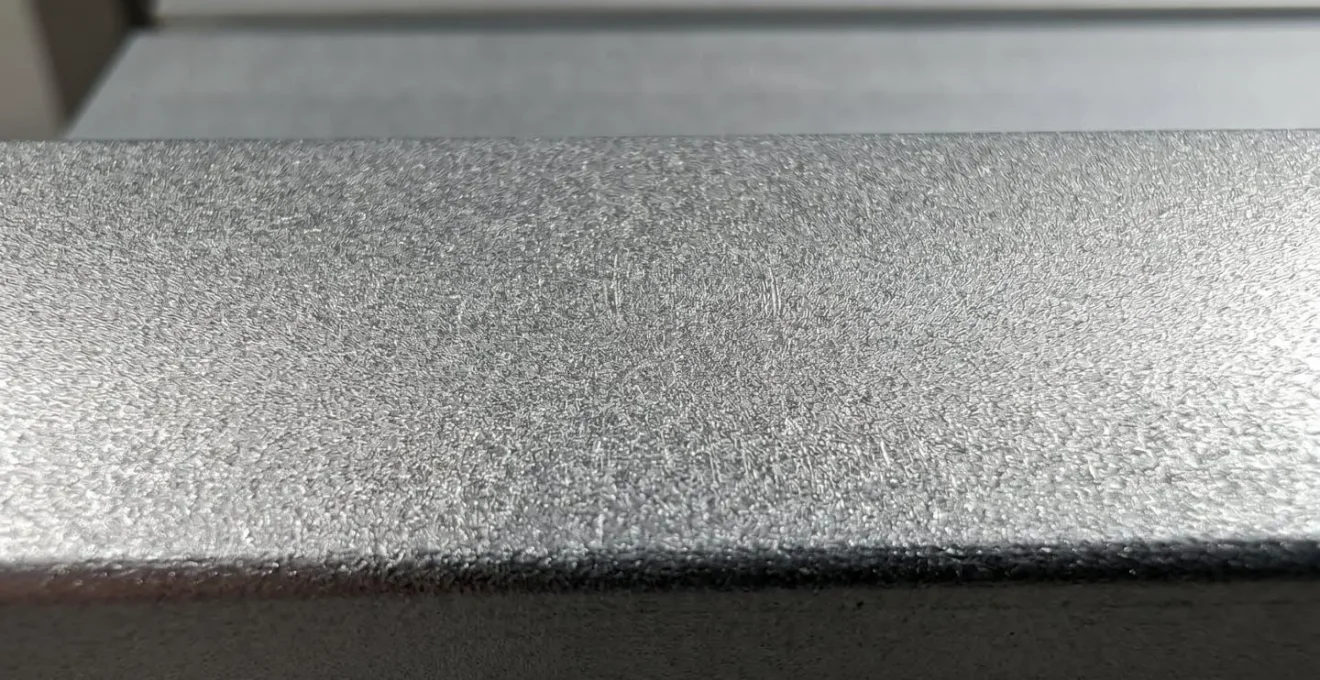 Fotografía macro en primer plano extremo de la textura superficial de aluminio anodizado mostrando micro-rugosidad mate característica