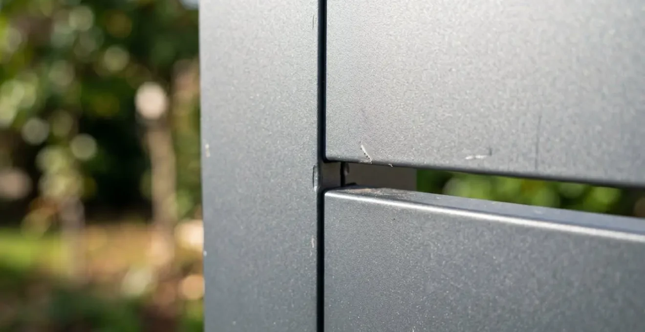 Primer plano extremo de la textura de un panel de valla de aluminio mostrando el acabado mate y las uniones entre lamas