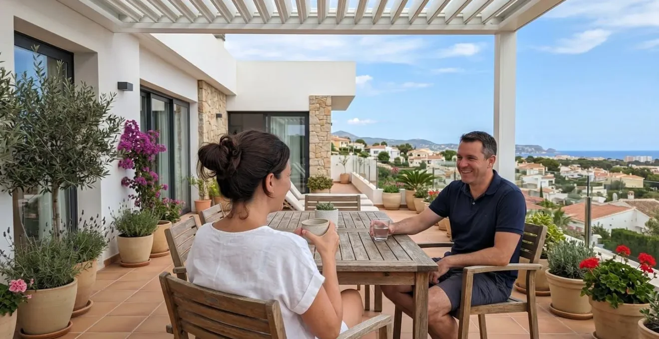 Una pareja relajándose en una terraza acondicionada bajo una pérgola contemporánea, vistos de espaldas en un entorno residencial español luminoso
