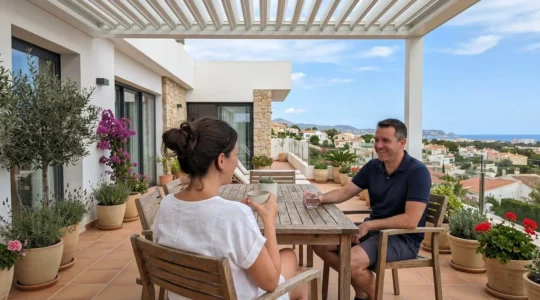 Una pareja relajándose en una terraza acondicionada bajo una pérgola contemporánea, vistos de espaldas en un entorno residencial español luminoso