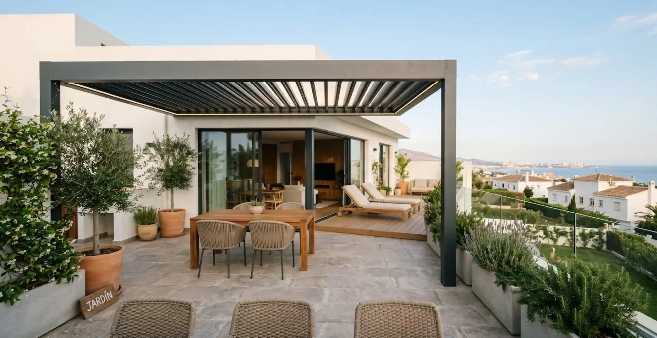 Vista panorámica de una terraza moderna española con pérgola bioclimática instalada, jardín cuidado y mobiliario contemporáneo en un entorno residencial luminoso